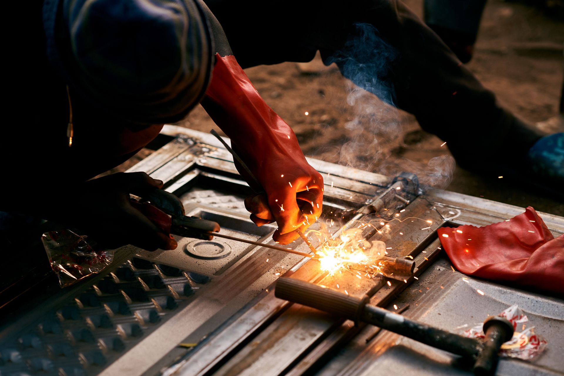 Close-up of an industrial worker welding metal, creating bright sparks.